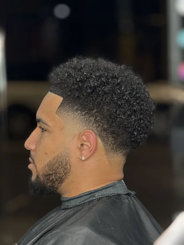 Curls on top with a taper and a shaped beard